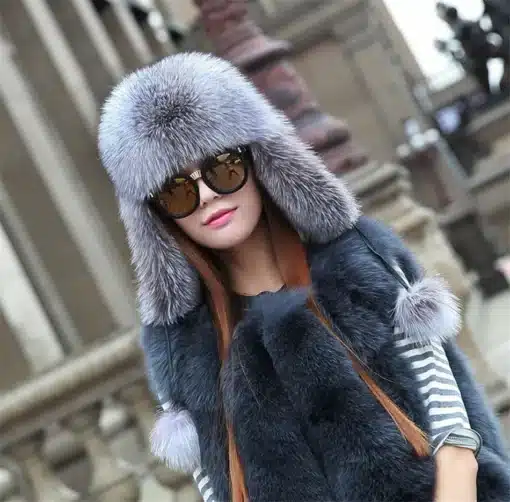 Rebase- või pesukarukarvaga läkiläkid naistele | E-pood Tootemaailm Naine kannab rebase- või pesukarukarvaga läkiläkit, mille hallikas karv on luksuslik ja soojapidav. Taustal on uhke arhitektuur, rõhutades toote elegantsust.