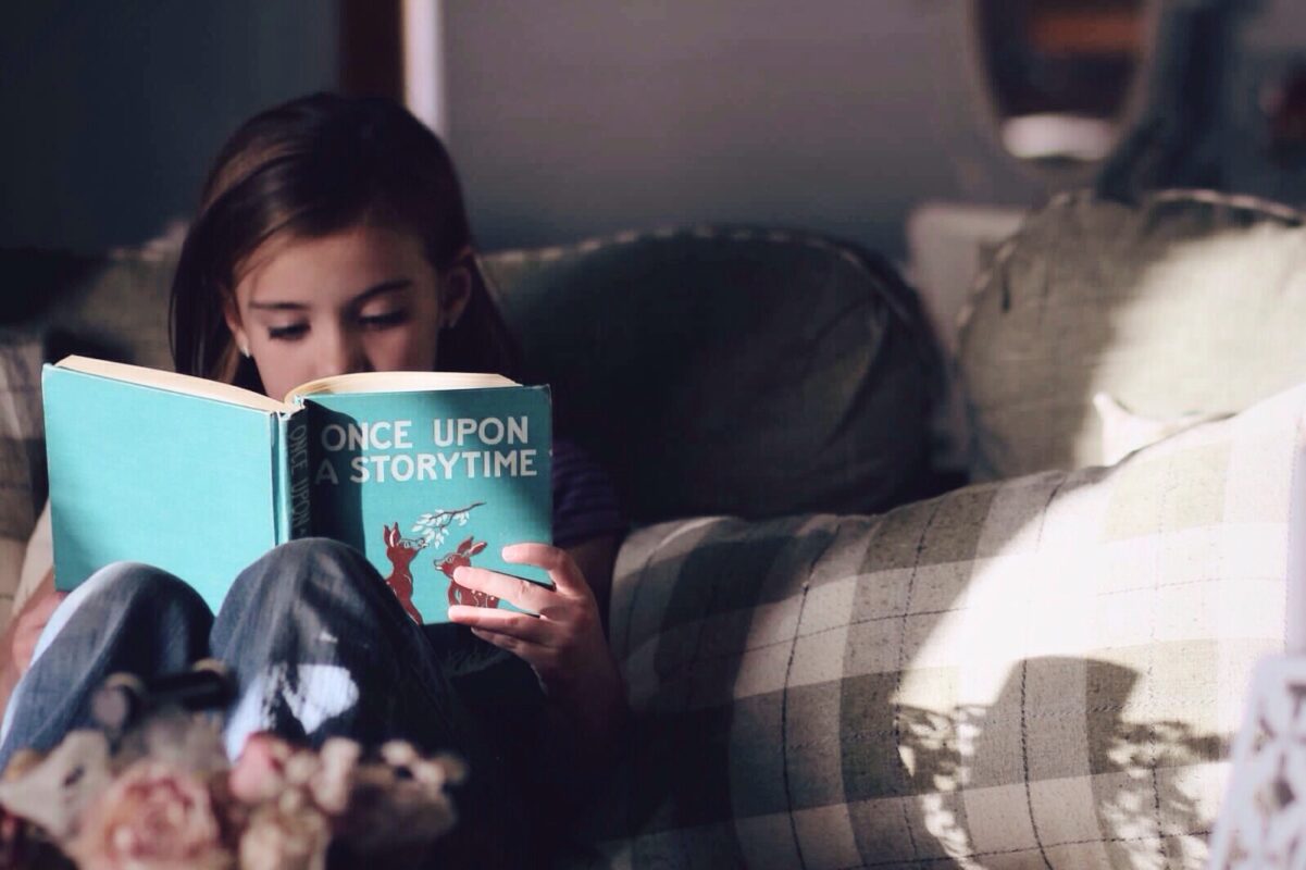 Kuidas õppida lugema? | E-pood Tootemaailm Laps loeb diivanil raamatut 'Once Upon a Storytime'.