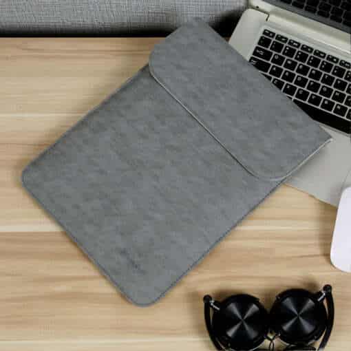 hall ja roosa macbooki ümbris laual koos avatud sülearvutiga