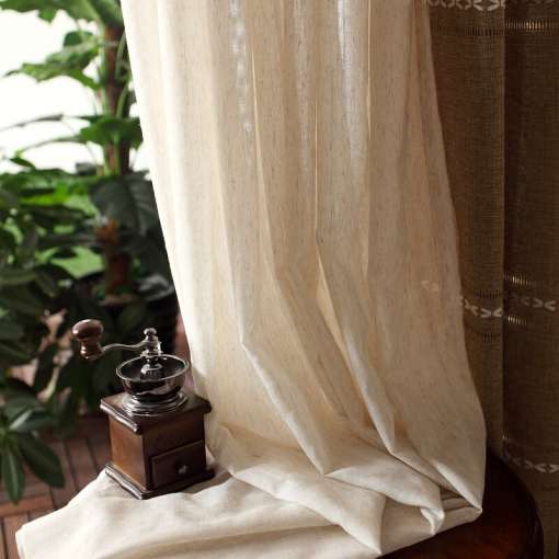 heledad retro stiilis kardinad, mis langevad elegantselt puidust lauale, taustal rohelised taimed