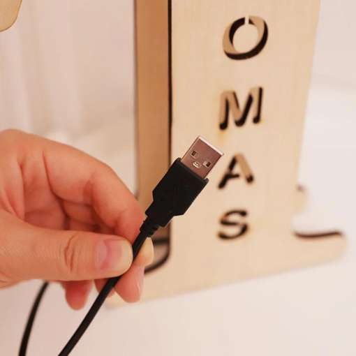 käsi hoiab usb-kaablit puidust alusel, millel on tähed