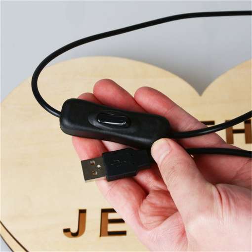 käes hoitakse musta juhtmega USB-kaablit lülitiga