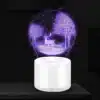valge alusega LED lamp, millel on 3D pilt hirvest ja puudest lilla valgusega