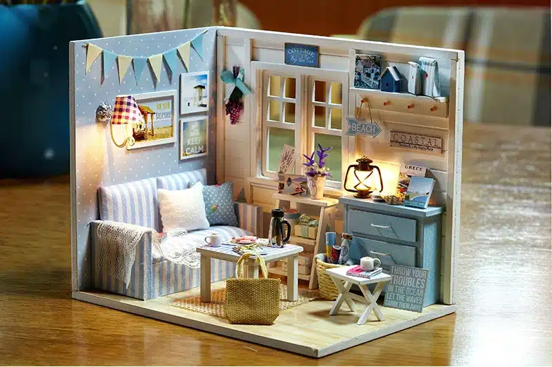 puidust miniatuurne möbleeritud nukumaja tuba, millel on diivan, laud ja lamp