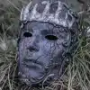 tume hall mask, millel on krooni kujundus ja keerulised mustrid, asetatud rohu sisse