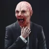 hirmutav zombi mask, millel on avatud suu ja verised detailid, kantud ülikonnaga inimese poolt