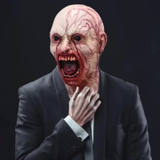 hirmutav zombi mask, millel on avatud suu ja verised detailid, kantud ülikonnaga inimese poolt