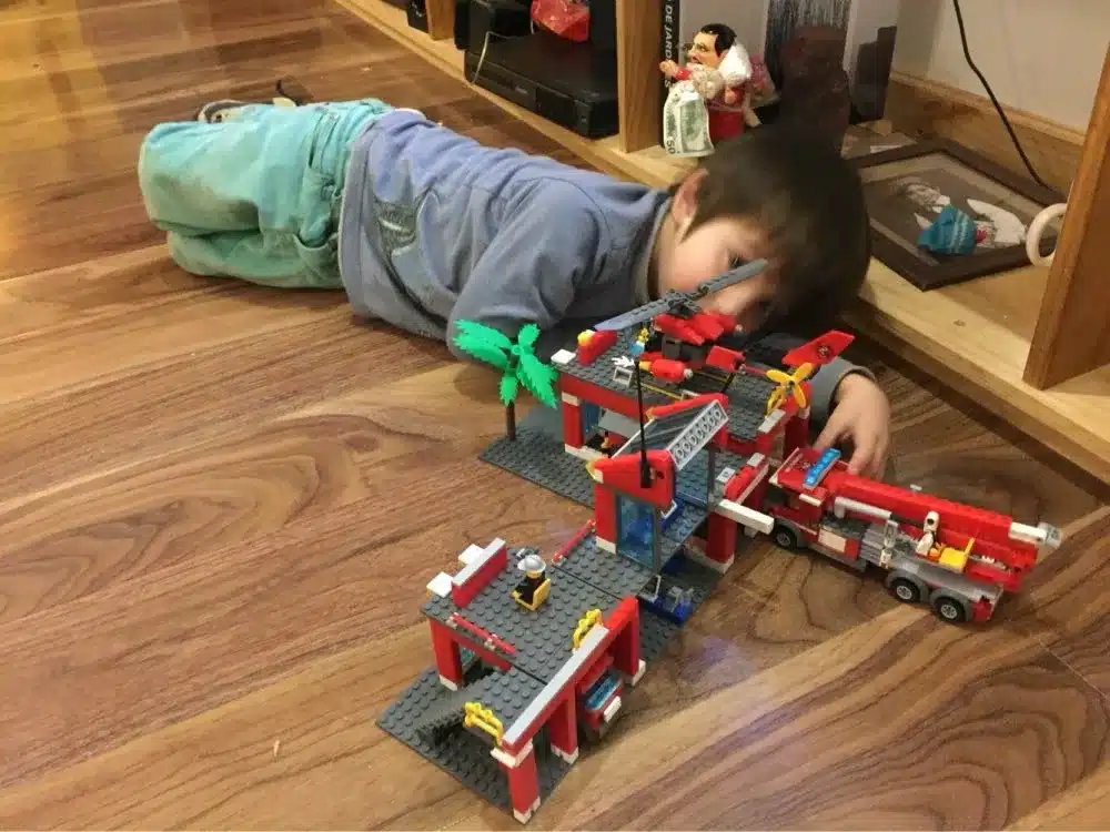 laps mängib põrandal lego tuletõrjedepoo komplektiga