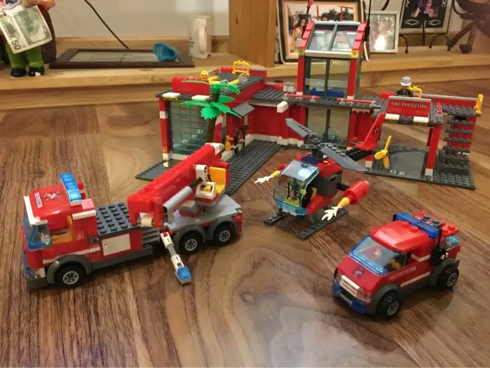 lego tuletõrjedepoo komplekt koos tuletõrjeautode ja helikopteriga puidust põrandal