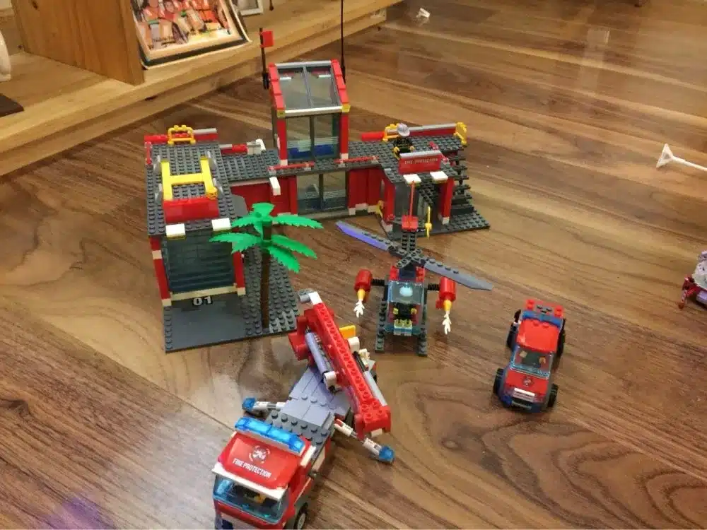 lego tuletõrjedepoo komplekt koos sõidukite ja helikopteriga puidust põrandal