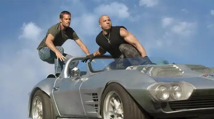kaks meest sportautol, üks kannab musta särki ja suurt risti kaelakeed
